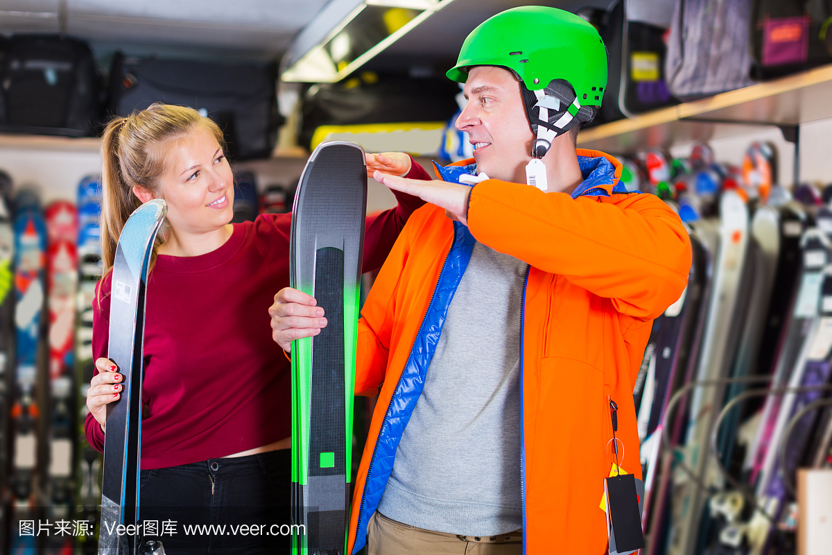 卖家女士正在帮助男士在设备上选择滑雪板